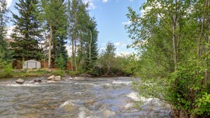 A river flowing through a forested area with a small shed and wooden fence in the background. - 101 Streamside Lane 2 Bedroom Condo by RedAwning (Frisco)