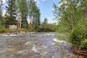 Escape to a serene riverside haven surrounded by lush greenery and tall trees.