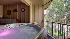 A hot tub on a balcony with a view of trees and a clock on the wall. - 101 Streamside Lane 2 Bedroom Condo by RedAwning (Frisco)