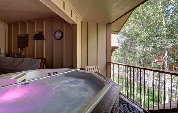 Relax in a hot tub on the balcony overlooking lush green surroundings.