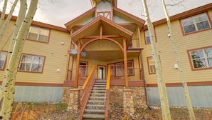 A two-story building with a stone foundation, a wooden staircase, and a covered porch. - 101 Streamside Lane 2 Bedroom Condo by RedAwning (Frisco)