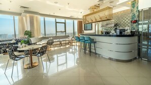 Un moderno vestíbulo de hotel con zona de estar, un bar y un amplio ventanal con vistas a la ciudad.