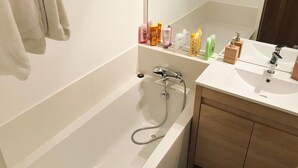 A modern bathroom with a bathtub, a sink, and a mirror. - South-facing apartment in resort center (Isola 2000)