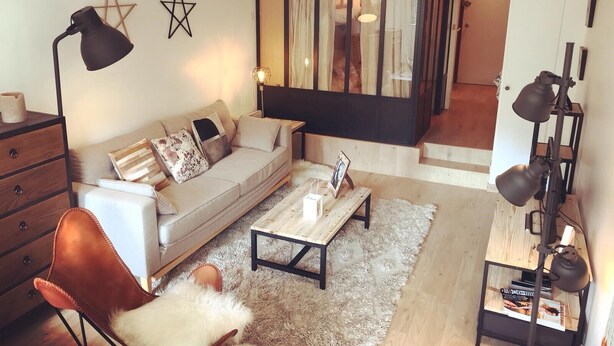 A modern living room with a sofa, coffee table, and a lamp. There is a star decoration on the wall and a staircase leading to another room. - South-facing apartment in resort center (Isola 2000)