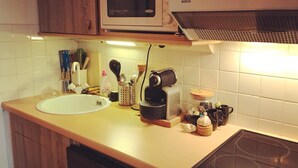 A kitchen with a microwave, toaster, sink, and a stovetop. - South-facing apartment in resort center (Isola 2000)