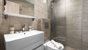 A modern bathroom with a large sink, a mirror, and a shower.