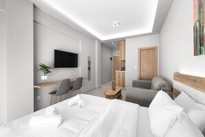 Una habitación de hotel moderna con una cama grande, un escritorio con una silla, un televisor y una planta pequeña.