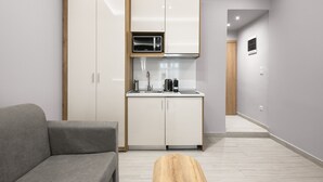 A compact kitchen with white cabinets, a microwave, and a sink.