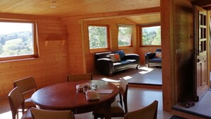 Una cabaña de madera con comedor, sofá y chimenea.