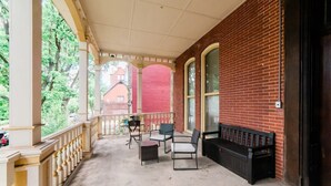 Une véranda couverte avec un mur en briques, un banc et du mobilier d’extérieur.