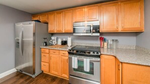 Une cuisine avec des meubles en bois, un réfrigérateur en acier inoxydable, un four à micro-ondes et un four traditionnel.