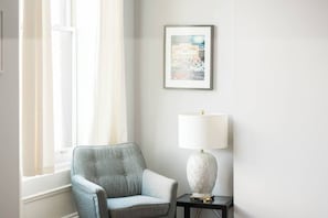 A room with a window, a framed picture on the wall, a lamp on a side table, and a chair. - Parking - Walkable - GroupStays - Washer (Pittsburgh)