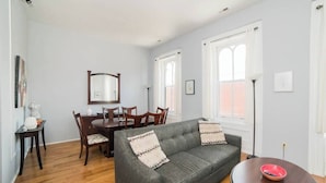 A living room with a gray sofa, wooden dining table, chairs, and a round coffee table. - Parking - Walkable - GroupStays - Washer (Pittsburgh)