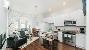 Una cocina moderna con armarios blancos, una estufa de acero inoxidable y un microondas.