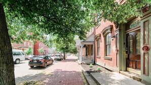 A street with parked cars, a brick sidewalk, and a building with a porch and large windows. - Studio Suite - No Steps - Walkable & Free Parking (Pittsburgh)