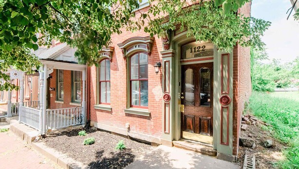 A brick building with a number '1122' on the door, a porch with a railing, and a small garden area. - Studio Suite - No Steps - Walkable & Free Parking (Pittsburgh)