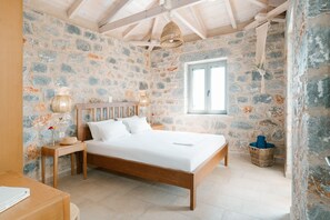 A bedroom with a stone wall, wooden bed frame, and a window.