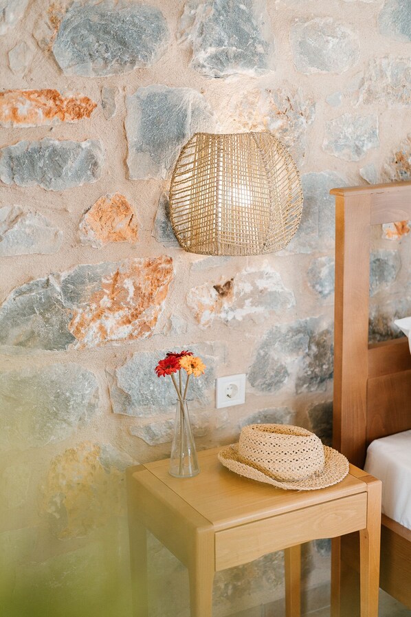 A stone wall with a woven lamp and a vase with flowers on a wooden table. - Dione Villa 3: private pool - amazing sea view - traditional minimal stone villa (STOUPA)