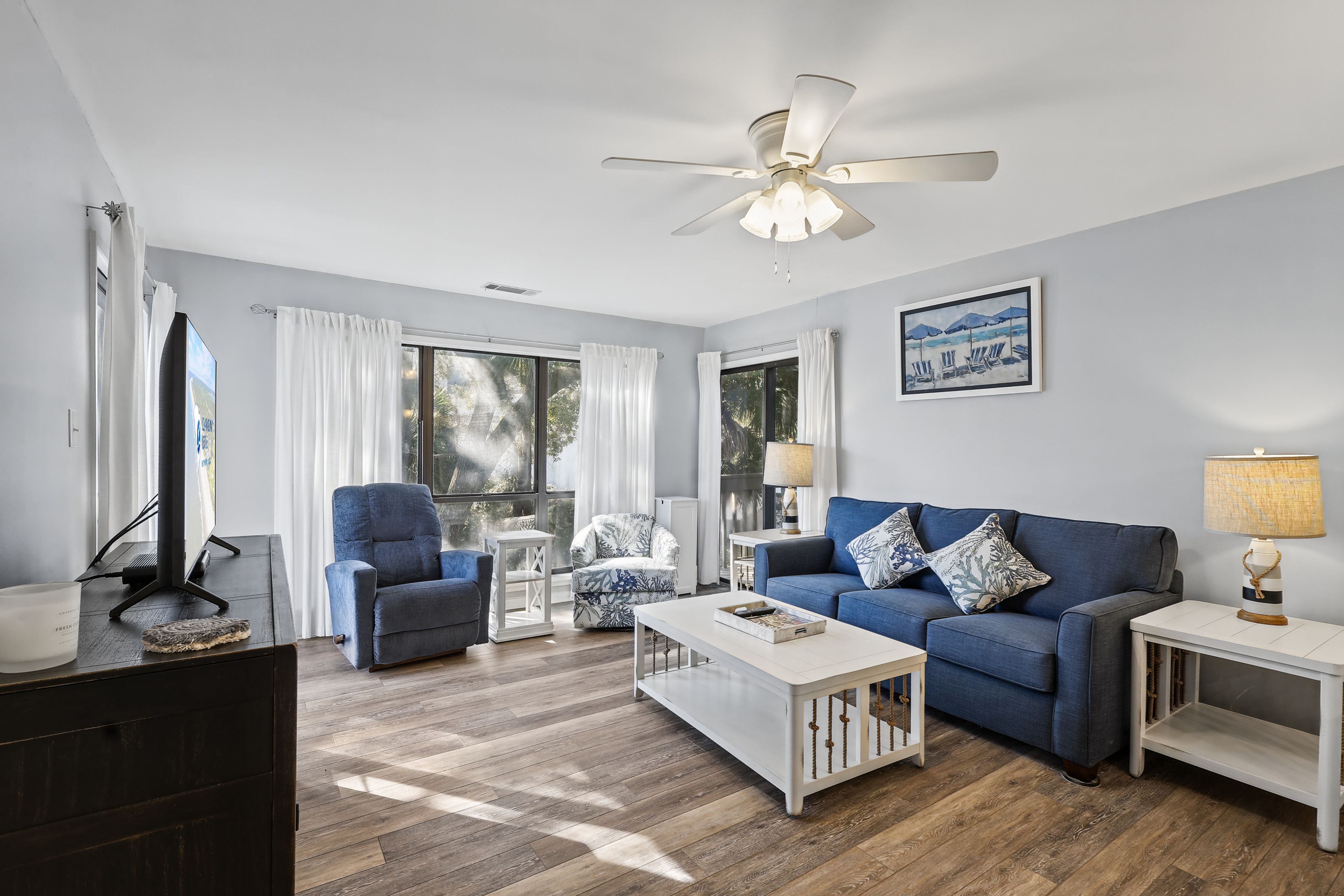 Un salon moderne avec un canapé bleu, une table basse blanche et un ventilateur de plafond.