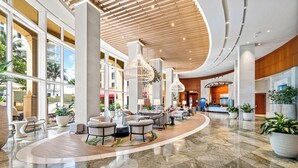 A spacious lobby with a curved marble floor, large seating areas, and a central reception desk.