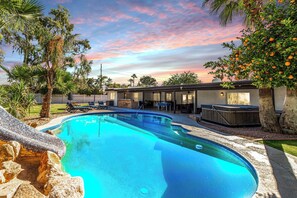Et moderne hus med swimmingpool, udendørs møbler og jacuzzi.