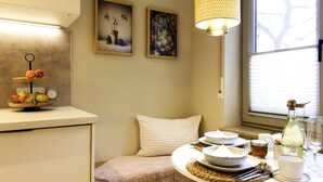 A cozy kitchen with a fruit display, a dining table set for two, and artwork on the walls. - Beautiful apartment 2 in Bad Neustadt next to Rhön Klinikum Campus (Bad Neustadt an der Saale)