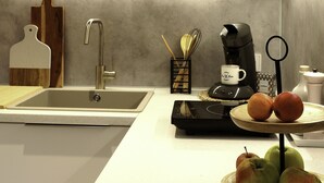 A kitchen with a sink, a coffee maker, and a fruit bowl with apples and oranges. - Beautiful apartment 2 in Bad Neustadt next to Rhön Klinikum Campus (Bad Neustadt an der Saale)