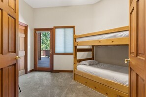 A room with a bunk bed, a door leading to an outdoor area, and a window with blinds.