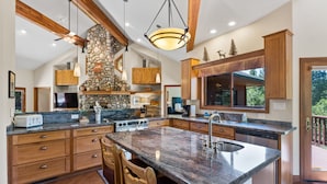 A spacious kitchen with granite countertops, wooden cabinets, and a large island with bar stools.