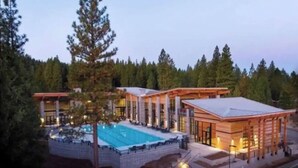A resort with a swimming pool, multiple guest rooms, and a forested backdrop.