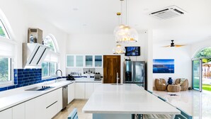 A modern kitchen with a central island, white cabinetry, and blue accents. - Spacious Villa w/ Private Pool – Ideal for Groups, Steps to Tamarindo Beach (Tamarindo)