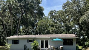 A single-story house with a patio area, a small lawn, and a large tree in the background. - Waterfront Retreat with Kayaks (Inverness)