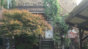 Un immeuble à plusieurs étages, avec un escalier en bois menant à l’entrée.