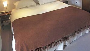 A neatly made bed with a brown blanket and white pillows in a hotel room. - 2 bedroom accommodation in Bakewell (Bakewell)