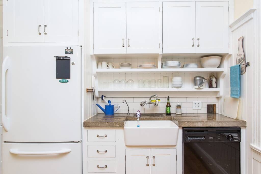 A kitchen with white cabinets, a white refrigerator, a sink, and a dishwasher.