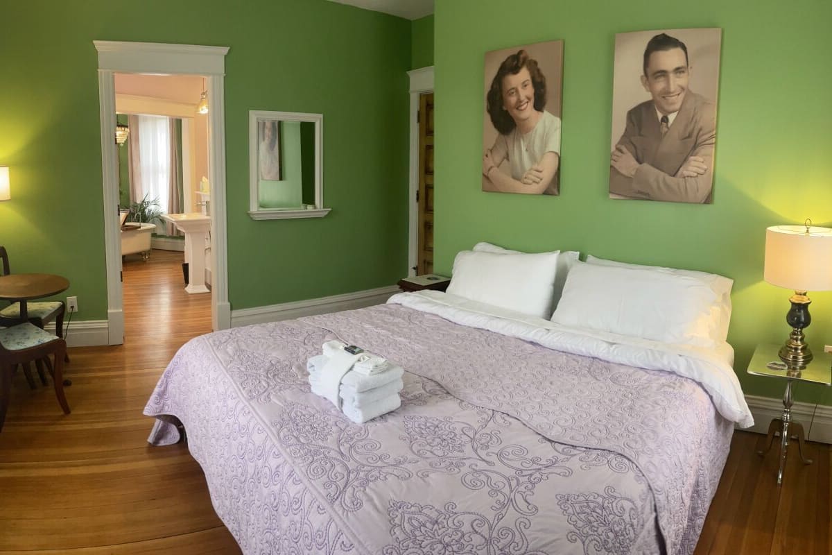 Um quarto com uma cama, uma cadeira, uma escrivaninha e um espelho.