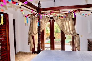 A bedroom with a bed, curtains, and a view of the outside.