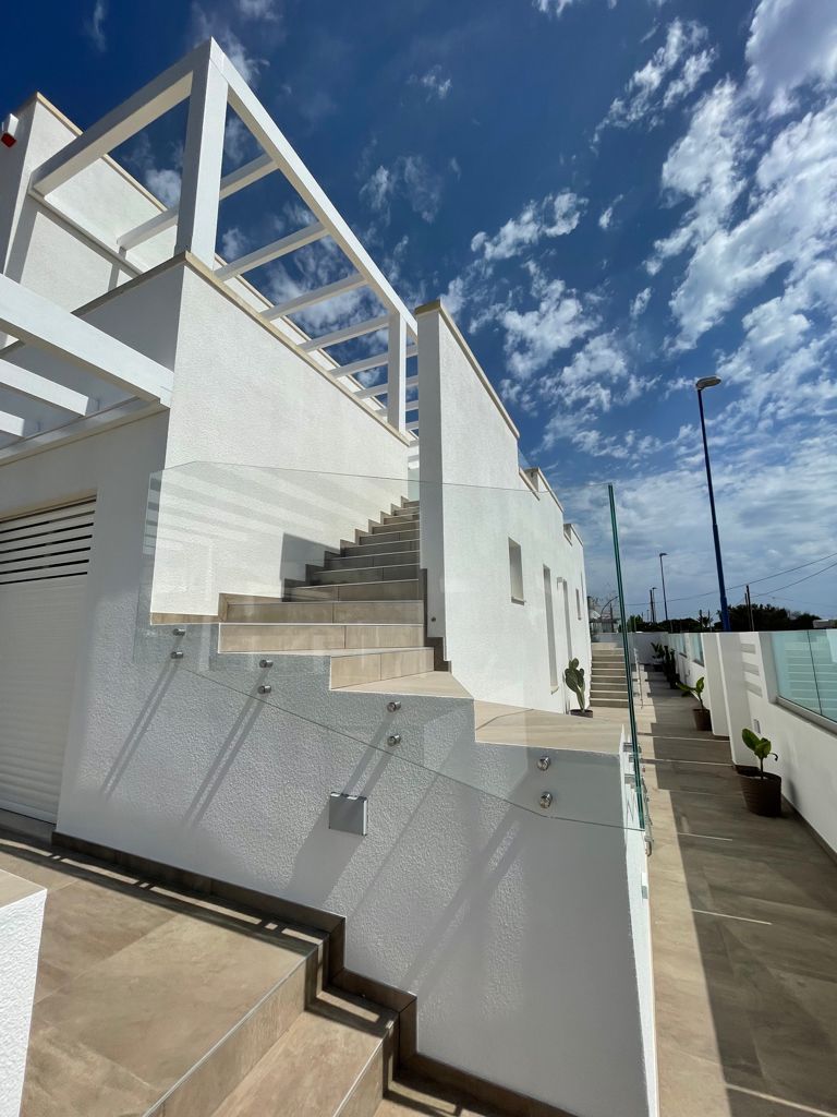 A modern building with a staircase leading to a covered area, surrounded by a white exterior and a clear sky.
