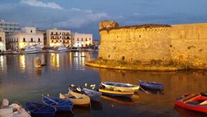 Una orilla con barcos amarrados cerca de una muralla de piedra histórica.