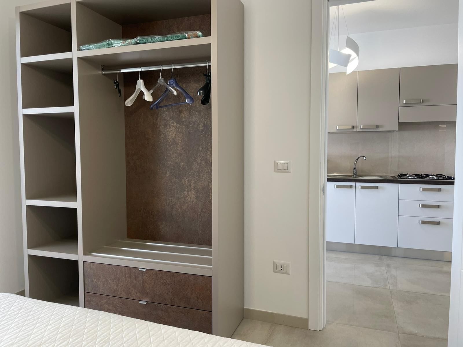 A modern apartment with a walk-in closet, a kitchenette, and a bed.