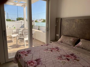 A bedroom with a bed, a window, and a view of an outdoor patio area. - Elite Luxury Residence (Racale)