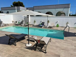 A pool area with lounge chairs, umbrellas, and a small table. - Elite Luxury Residence (Racale)