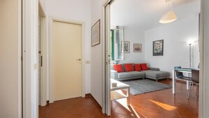 A living room with a sofa, a coffee table, and a dining area with a table and chairs. - Bright apartment in Via Ginori, in the heart of the Testaccio district (Rome)