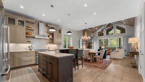 A spacious kitchen with a large island, wooden cabinets, and pendant lighting.