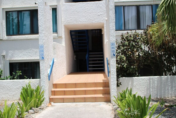 A building entrance with a set of stairs leading to a door, surrounded by plants and a white wall. - ON the Beach...With a VIEW!!! The 2 bedroom condo. The Beachfront Princesse (Christiansted)