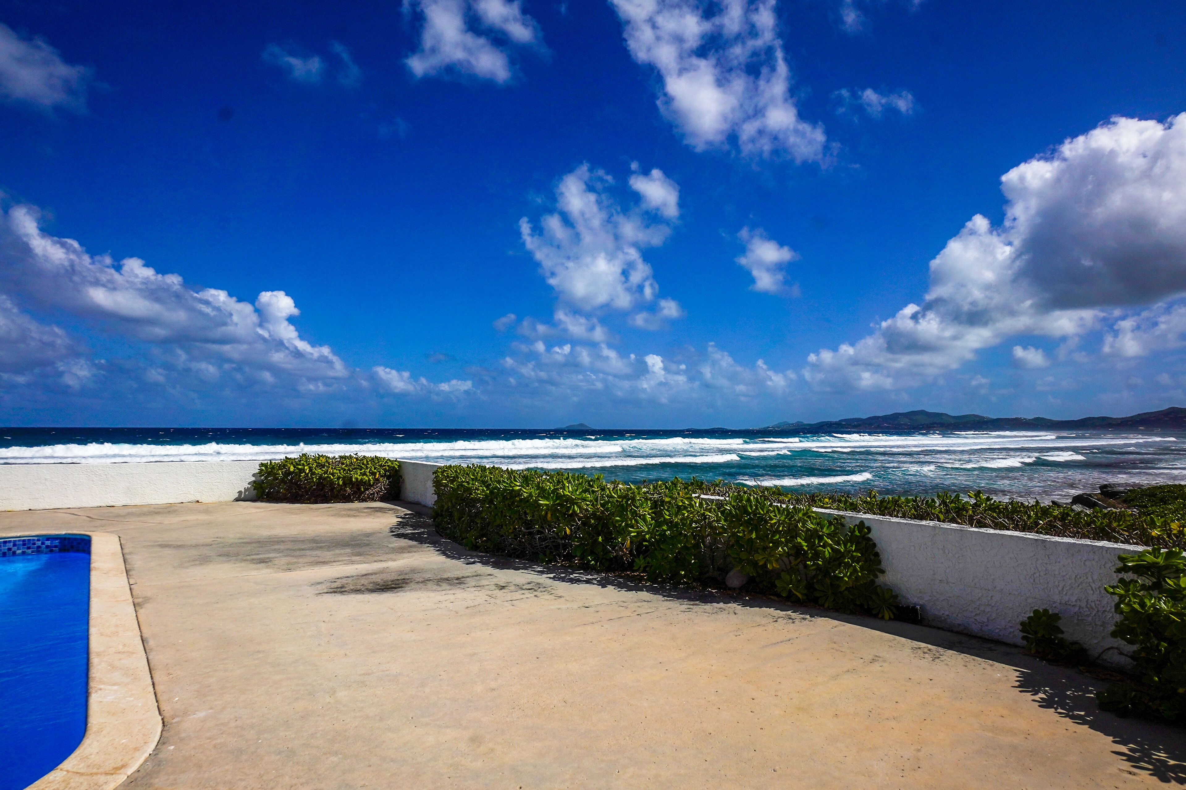 Área da piscina com vista para o oceano e a praia.
