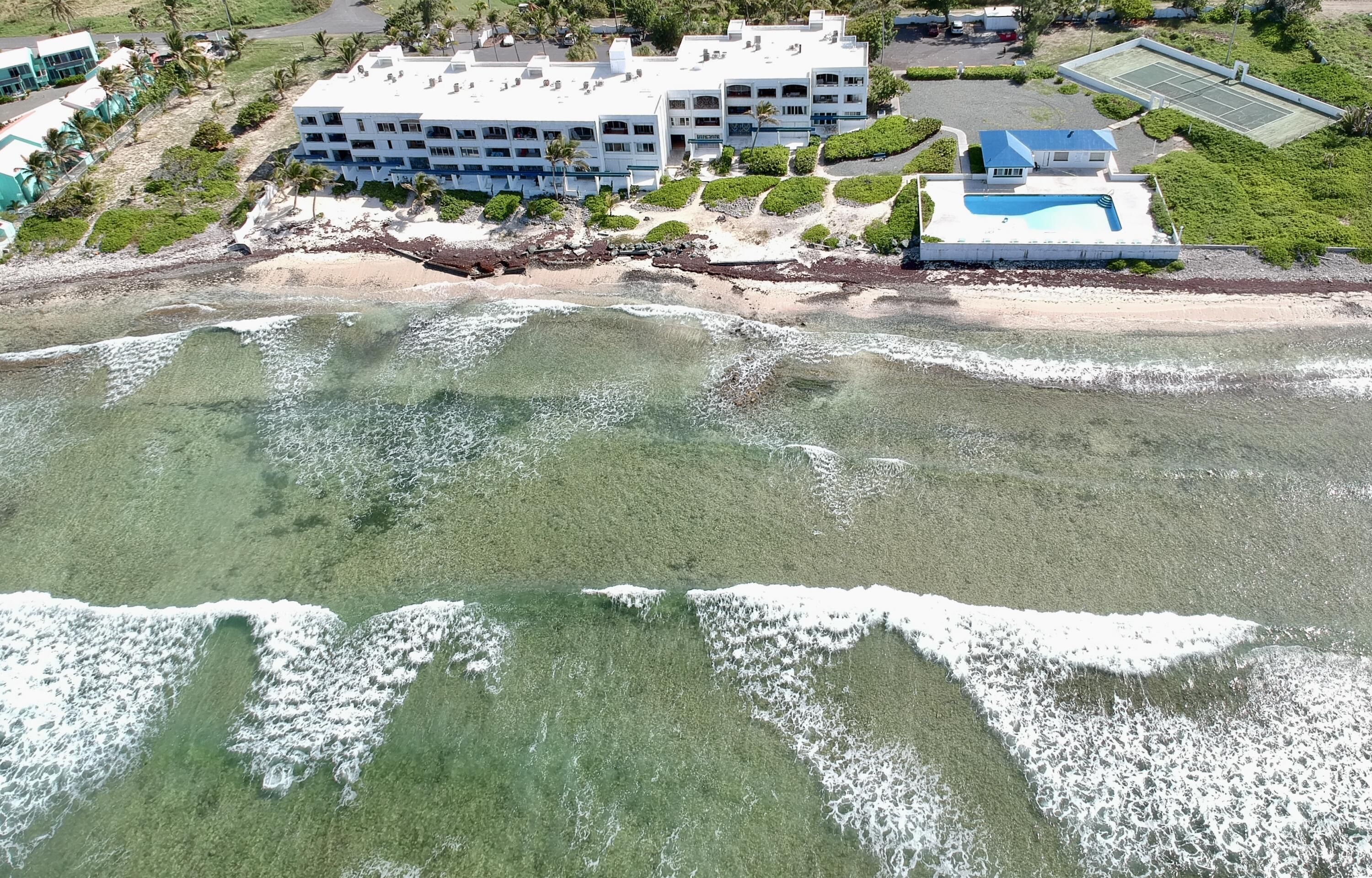 Ett flygbildsbild av ett hotell vid stranden med flera byggnader, en swimmingpool och ett område med strand.