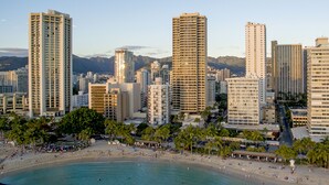 Un paisaje urbano costero con rascacielos, una playa y palmeras.