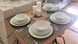A modern kitchen with a marble countertop, a built-in sink, and a dining area set with white plates, glasses, and a candle centerpiece. - Principe Real Central Home - Free Airport Transfer (Lisboa)