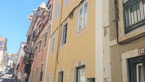 A narrow street lined with multi-story buildings, featuring balconies and a cobblestone sidewalk. - Principe Real Central Home - Free Airport Transfer (Lisboa)